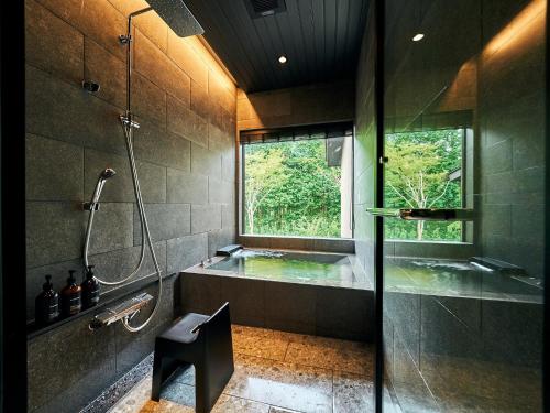 a bathroom with a shower and a tub and a window at Rakuten STAY VILLA Hakone Sengokuhara South Wing 103 BBQ Terrace capacity of 10 persons in Hakone