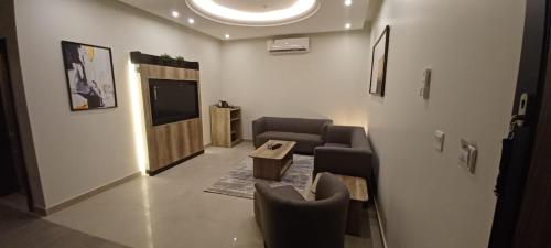 a living room with chairs and a table and a tv at المكارم بارك للشقق المخدومة -درجة التصنيف- اقتصادية in Jeddah