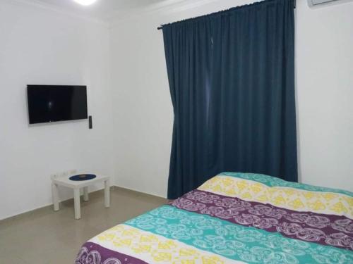 1 dormitorio con 1 cama, TV y ventana en Bright Apartment at Punta Cana WIFIAcElectIronParking en Punta Cana