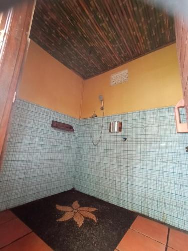 a bathroom with a shower and a tile wall at Puri Sunny Camp in Munduk