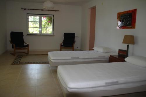 A dos Francos的住宿－Cozy Villa Near Obidos With Private Swimming Pool，客房设有两张床、两把椅子和窗户。