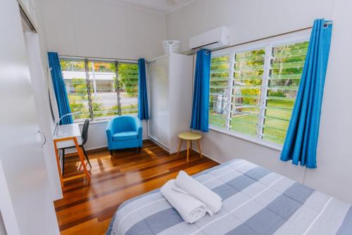 a bedroom with a bed and two windows with blue curtains at Kooyong Apartment 7 in Arcadia