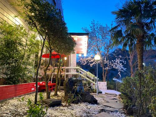 a garden with a bench and an umbrella at Hanamizuki Onsen Resort in Ito