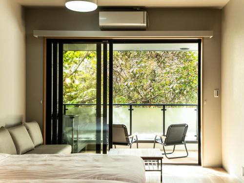 a bedroom with a bed and a balcony with chairs at Rakuten STAY MOTEL Nikko Kinugawa Dog Friendly Room in Nikko