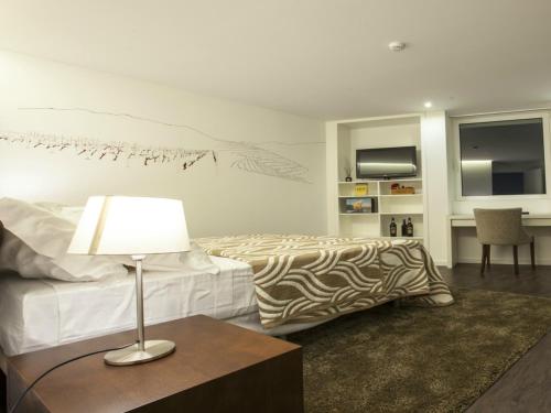 a bedroom with a bed and a table with a lamp at Casa Dona Maria Luiza in Torre de Moncorvo