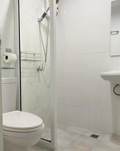 a white bathroom with a toilet and a shower at Boxsoon Nimman 2 # 4beds 3baths in Chiang Mai