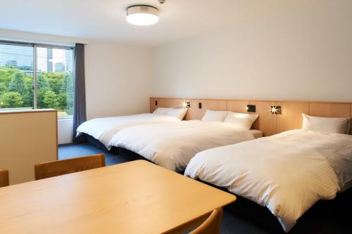a hotel room with two beds and a table at Rakuten STAY Osaka Station North Deluxe Fourth in Osaka