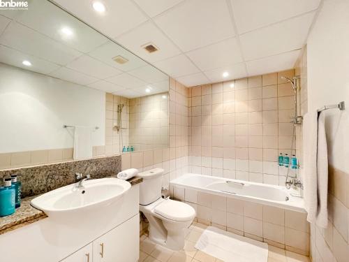 a bathroom with a toilet and a sink and a tub at bnbmehomes - Spectacular 1BR - Community View - 302 in Dubai