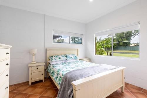 a white bedroom with a bed and a window at Boronia Avenue 18 in Mylestom