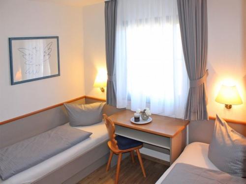 a hotel room with a couch and a desk and a bed at Ferienhaus Nr 102, Kategorie Komfort, Feriendorf Hochbergle, Allgäu in Karlsebene