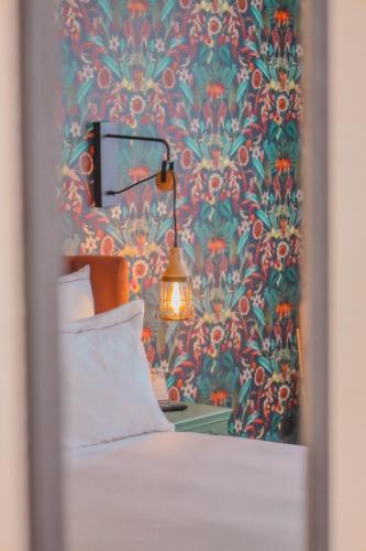 a bedroom with a wallpaper with a bed and a lamp at La Maison Hôtel Mulhouse Centre in Mulhouse