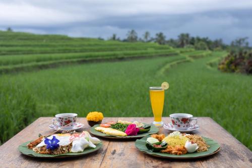 una tavola con due piatti di cibo e un bicchiere di succo d'arancia di Amarta Pesagi Retreat Tabanan a Tabanan