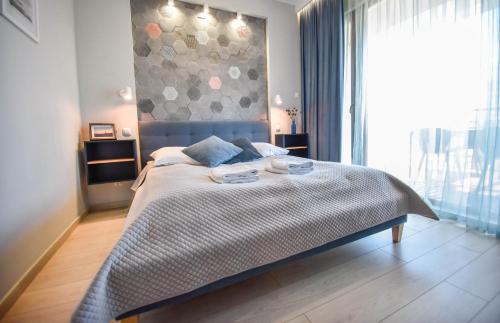 a bedroom with a bed and a large window at Apartamenty Na Wyspie - Baltic Park - Apartamenty z sypialnią i parkingiem - ul Uzdrowiskowa 24-34 in Świnoujście