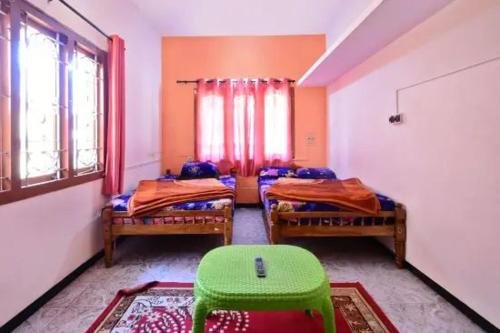 a room with two beds and a green chair in it at Long Wood Hills Cottage in Ooty