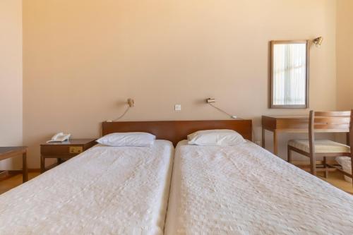 two beds in a bedroom with a desk and a mirror at Agia Markella in Chios