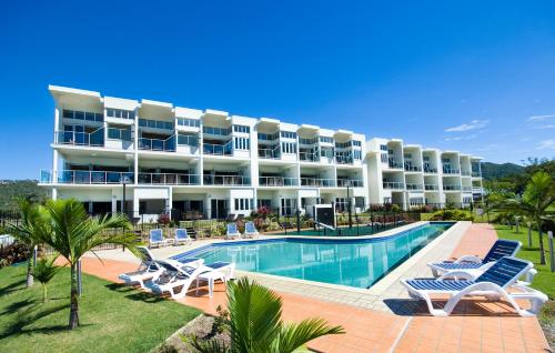 a large hotel with a swimming pool and lounge chairs at Beachside Magnetic Harbour Apartments in Nelly Bay