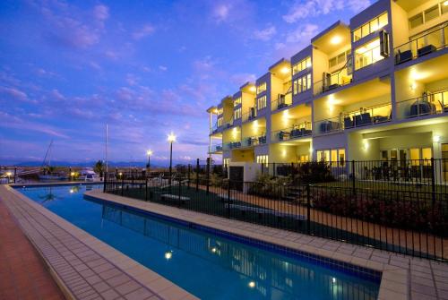 a hotel with a swimming pool at night at Beachside Magnetic Harbour Apartments in Nelly Bay