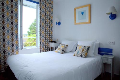 - une chambre avec un lit blanc et une fenêtre dans l'établissement L'Hôtel de Loctudy, à Loctudy