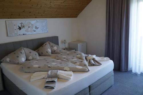 a bedroom with a bed with blankets and ties on it at Pension-Ferienwohnung Rotar in Faak am See