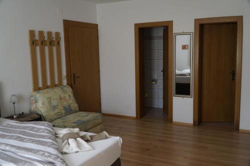 a room with a bed and a chair and a door at Pension-Ferienwohnung Rotar in Faak am See