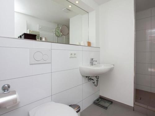 een witte badkamer met een toilet en een wastafel bij Zeelicht in Noordwijkerhout
