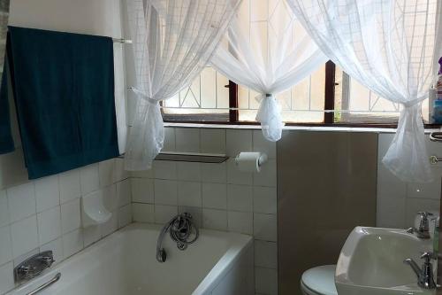 a bathroom with a tub and a toilet and a window at On The Beach @ South Sands.No 2 in Port Edward