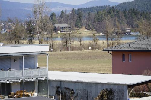 a house with a view of a field and a lake at Pension-Ferienwohnung Rotar in Faak am See