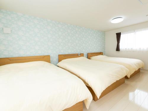 two twin beds in a room with blue walls at Kinugawa Station Front room B in Nikko