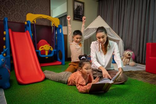 a woman reading a book to two children in a play room at Sofitel Philippine Plaza Manila in Manila