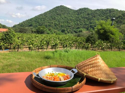 a bowl of food sitting on a table in front of a field at Baan I-A-run Resort in Pak Chong