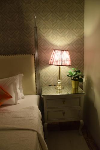a lamp on a night stand next to a bed at Dileep Kothi - A Royal Boutique Luxury Suites in Jaipur in Jaipur
