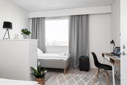 a bedroom with a bed and a desk and a window at Apartments Borg Wellamo in Pori