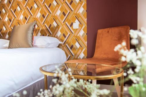 una camera con letto, sedia e tavolo in vetro di Hotel Le Petit Perier a Laval