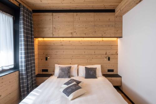 a bed in a room with a wooden wall at Residence Salvan in Corvara in Badia