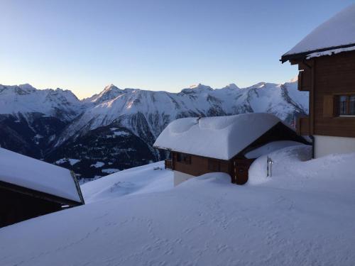 費爾施的住宿－Nido Alpino Fiescheralp，一座被雪覆盖的建筑,背景是群山