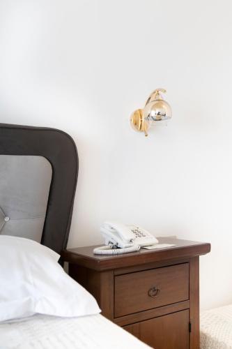 a bed with a nightstand with a phone on it at Agia Markella in Chios