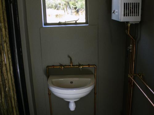 a white sink in a bathroom with a window at TimBila Camp Namibia in Omaruru