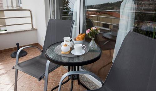 a table with a cup of coffee and a plate of food at Apartmani Škopac Rabac in Rabac