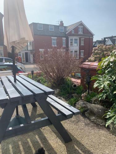a picnic table with an umbrella next to a house at The Woodleigh family hotel in Blackpool