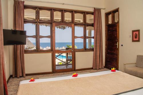 a bedroom with a large window with a view of the ocean at Veraclub Sunset Beach in Nungwi