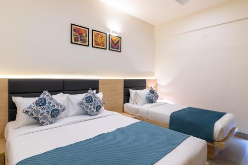 two beds in a room with white walls and blue pillows at Iris Suites in Bengaluru