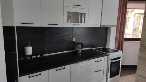 a kitchen with white cabinets and a black counter top at NETWORK apartment in Jajce