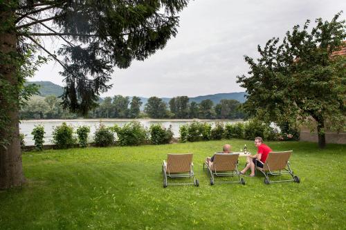 two people sitting at a table in chairs in the grass at Winzerhof - Gästehaus Stöger in Dürnstein