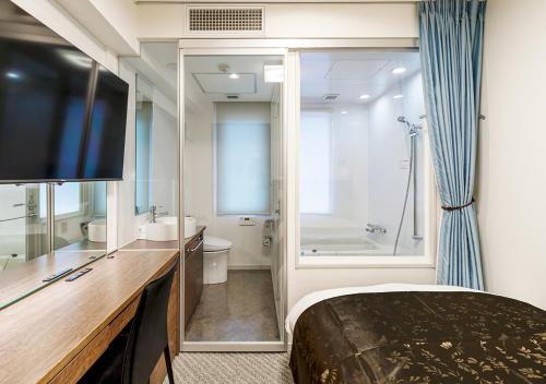 pokój hotelowy z łóżkiem i telewizorem oraz łazienką w obiekcie APA Hotel Kamata-Ekimae w Tokio