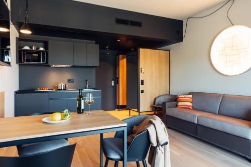 a kitchen and living room with a table and a couch at harry's home Telfs hotel & apartments in Telfs
