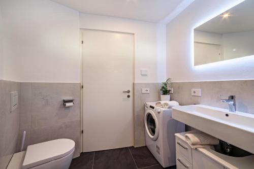 a white bathroom with a washing machine and a sink at Adler Living Gartenwohnung in Naturno