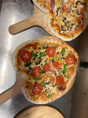 two pizzas with tomatoes and mushrooms on a table at Hotel Kammerhof in Mariastein