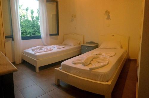 two beds in a room with a window at Sofia Rooms in Loutro