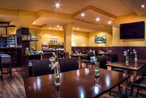 シュトゥットガルトにあるホテル アム ヴィルヘルムスプラッツのテーブルと椅子、薄型テレビ付きのレストランを提供しています。