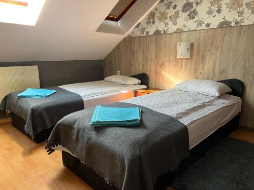 2 łóżka w pokoju z niebieskimi ręcznikami w obiekcie Zajazd Grodzki w Koninie
